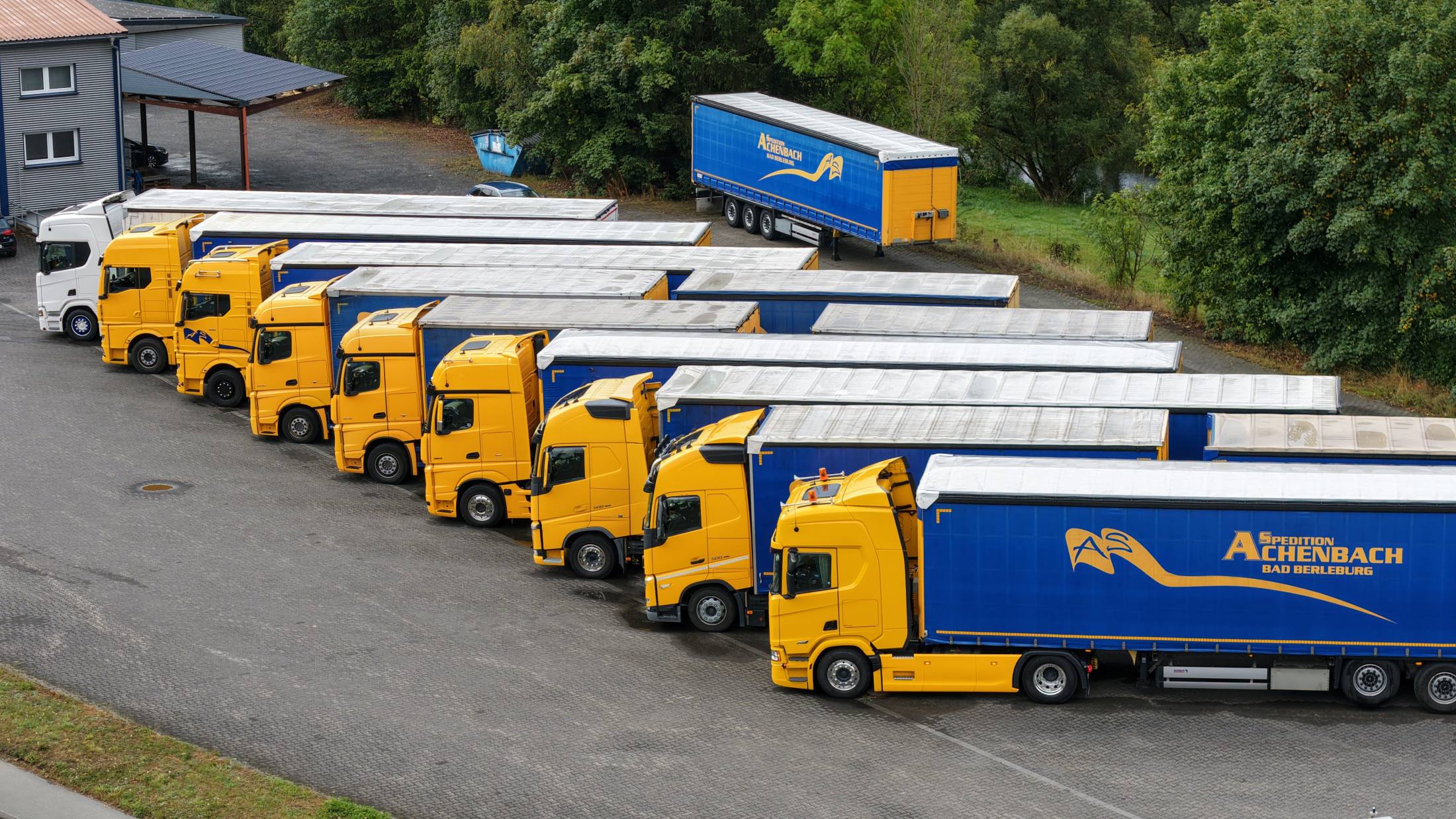 Reihe gelber Lkw auf dem Betriebshof der Spedition Achenbach
