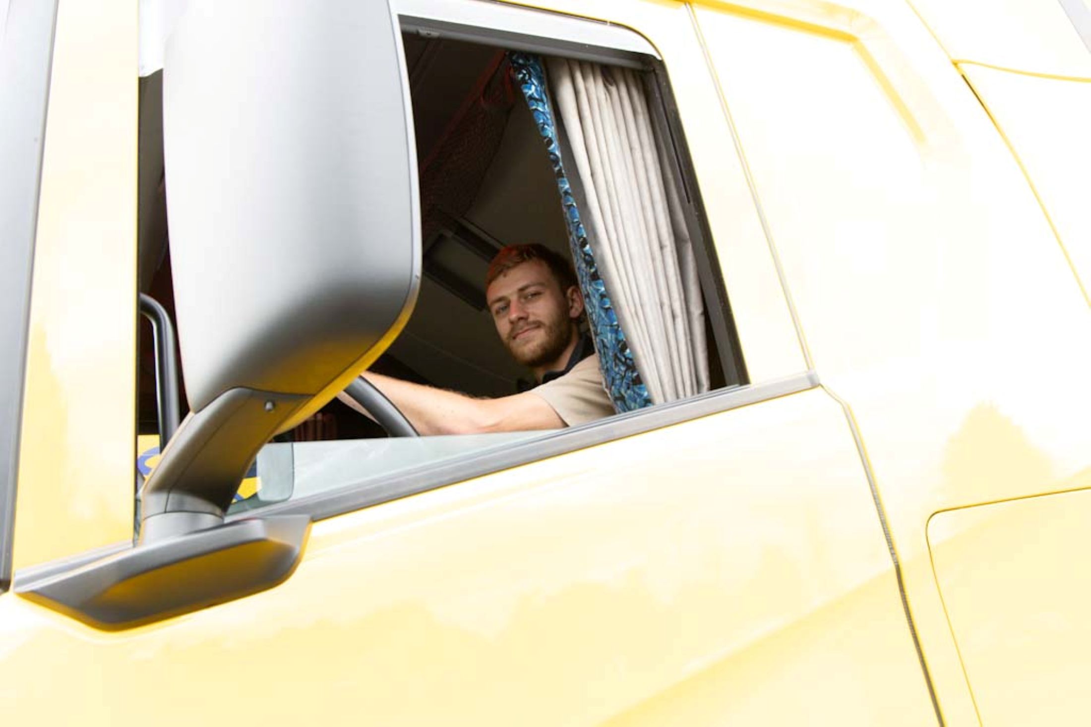 Berufskraftfahrer der Spedition Achenbach in gelbem Lkw unterwegs