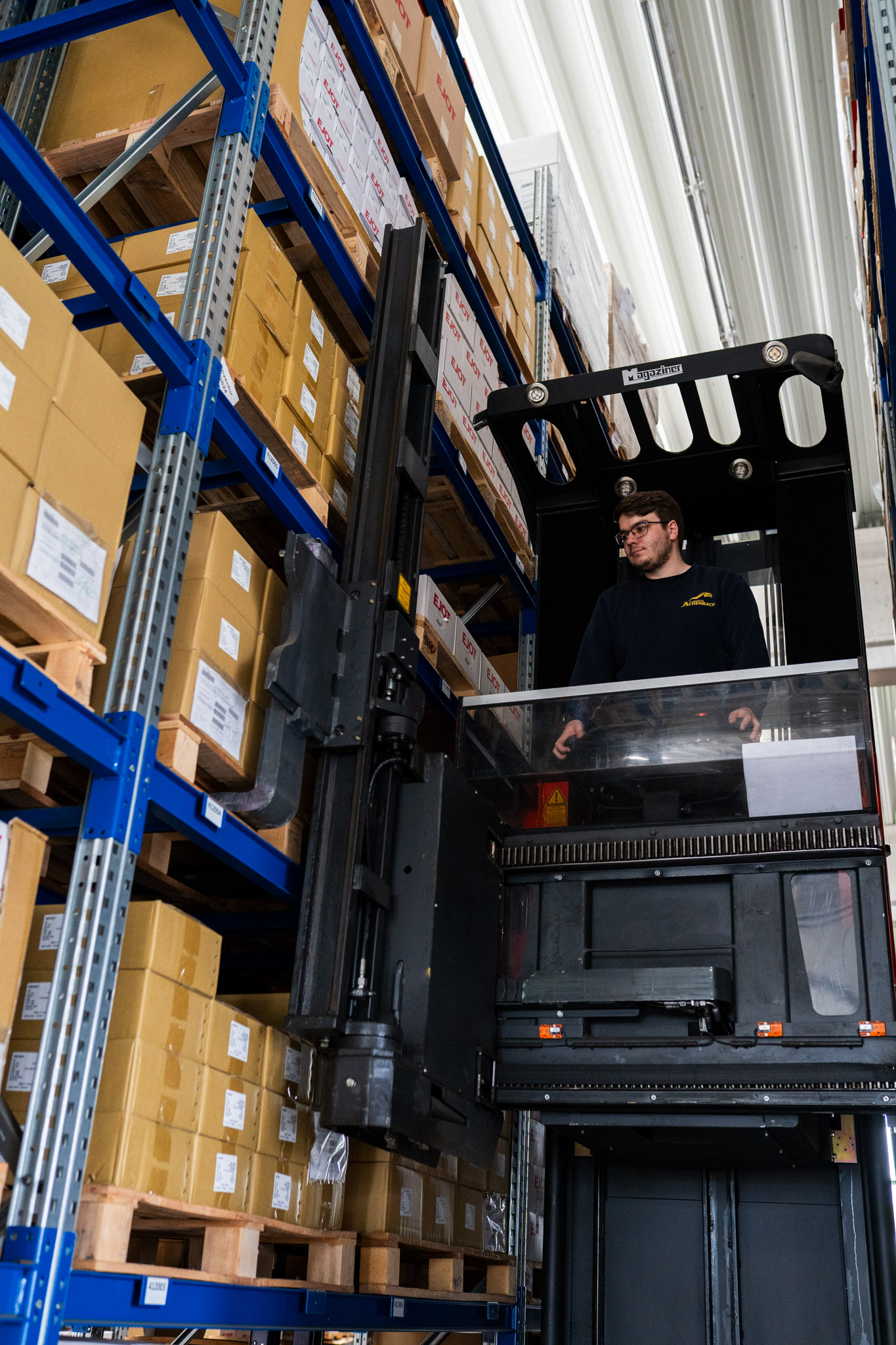 Mitarbeiterin der Achenbach Logistik im Hochregallager mit Paletten und Waren