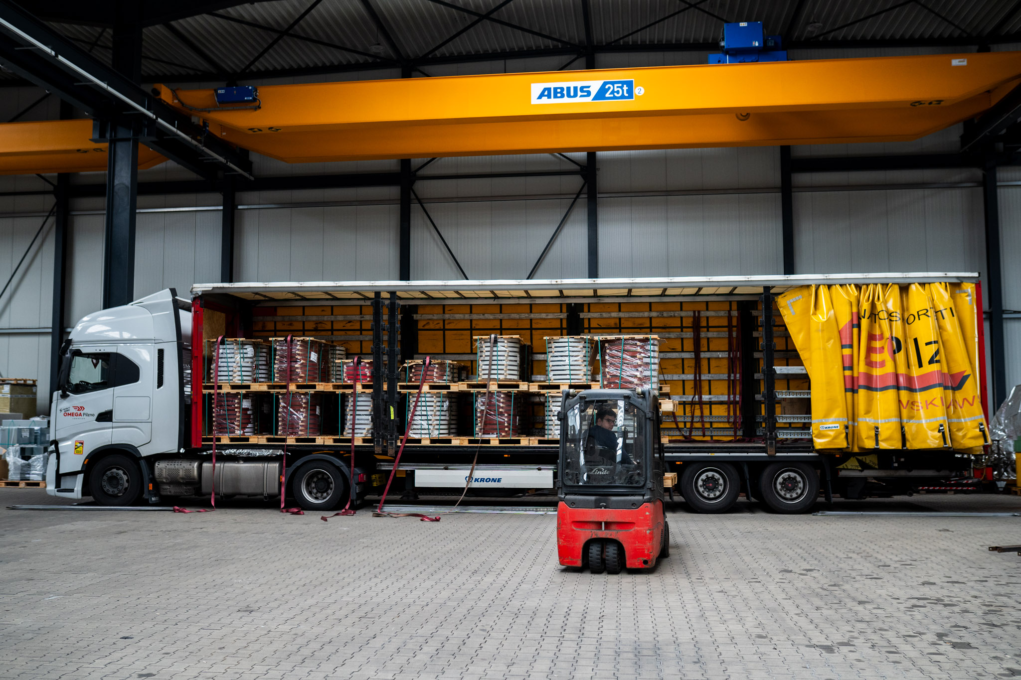 Verladung von Gütern über Rampe mit Kran und Stapler