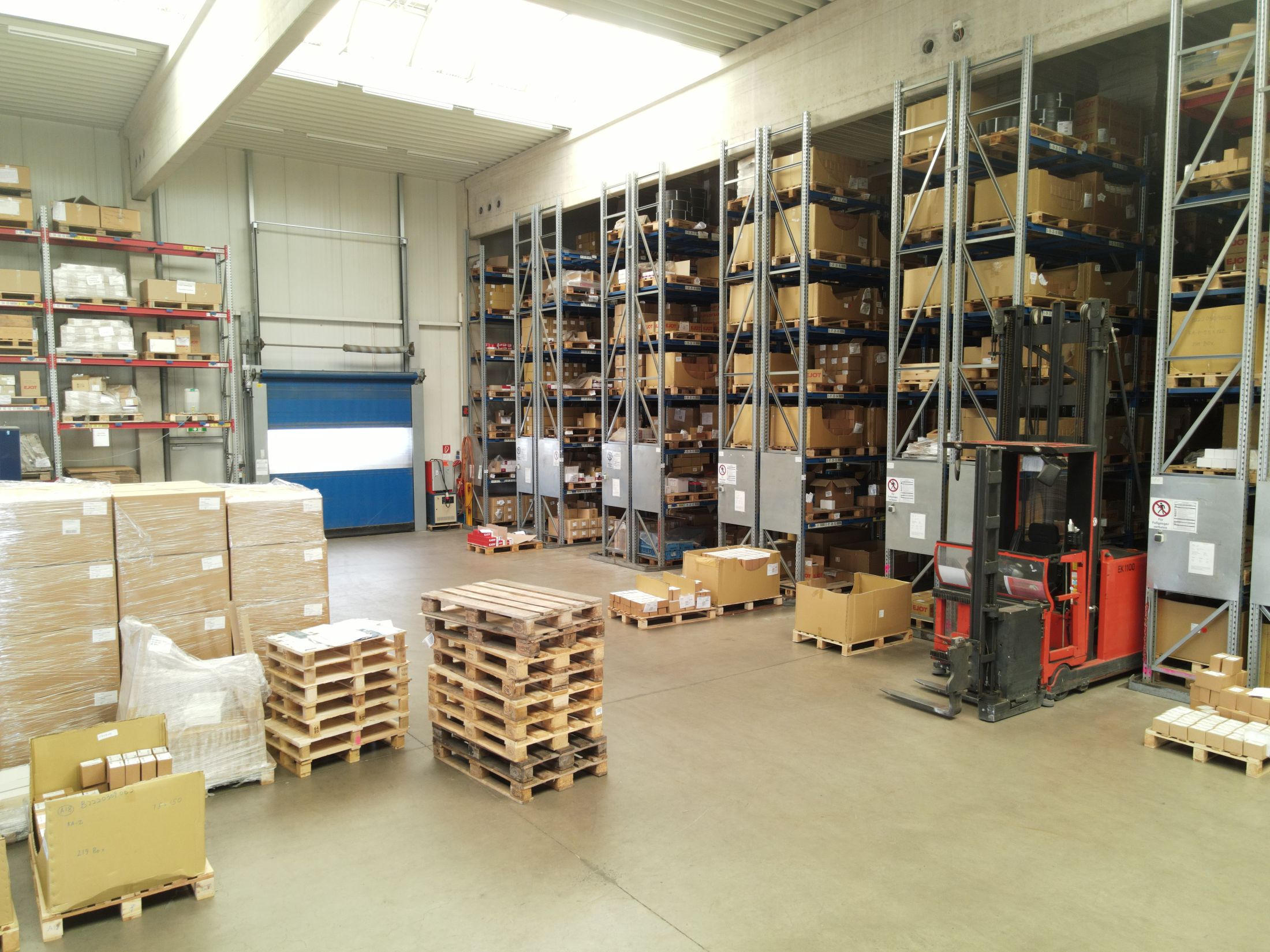 Lagerhalle mit hohen Regalanlagen und Gabelstapler bei der Arbeit