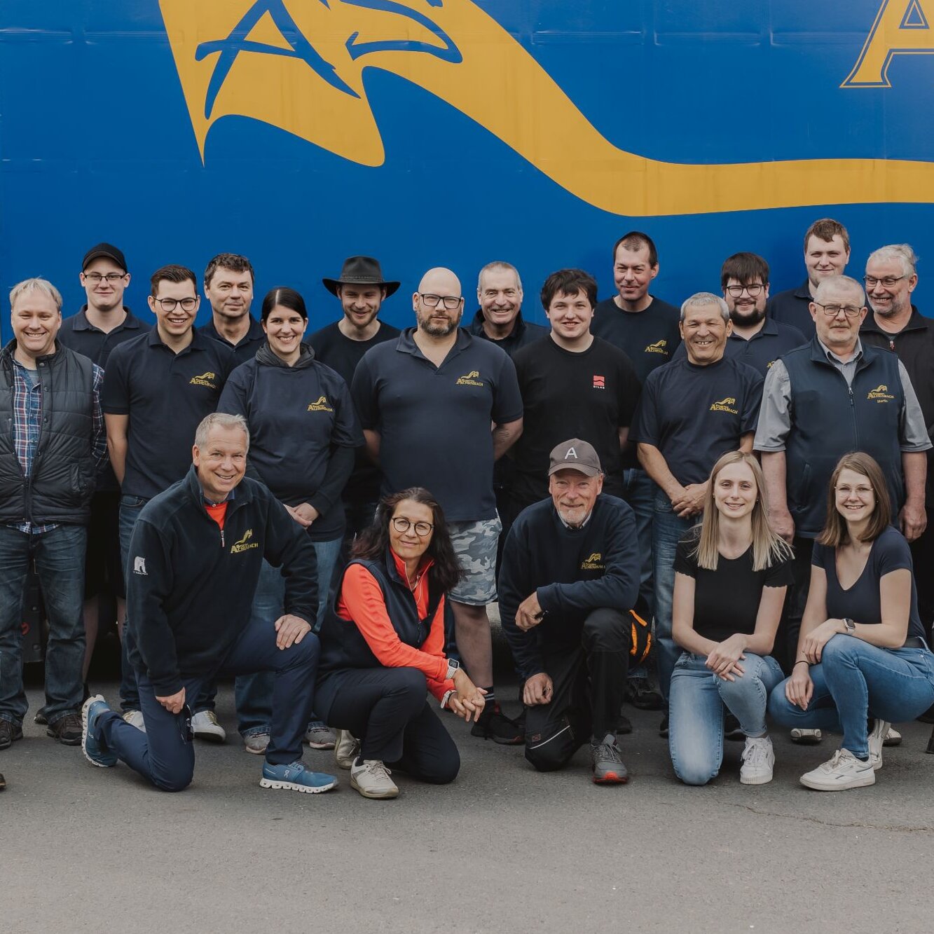 Gruppenfoto des Teams der Spedition Achenbach vor blau-gelbem Lkw