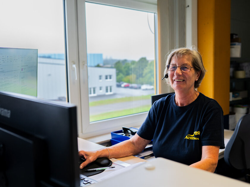 Angelika Schneider, Lagermanagement bei Achenbach Logistik, am Schreibtisch mit Blick ins Lager